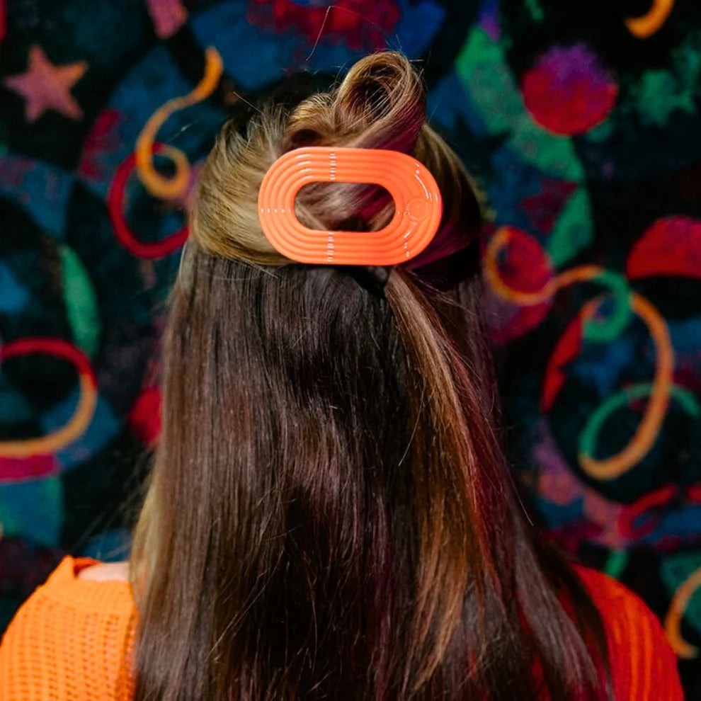 Doodlations Coffee Bar & Boutique orange ribbed oval hair clip with a flat, rounded design.