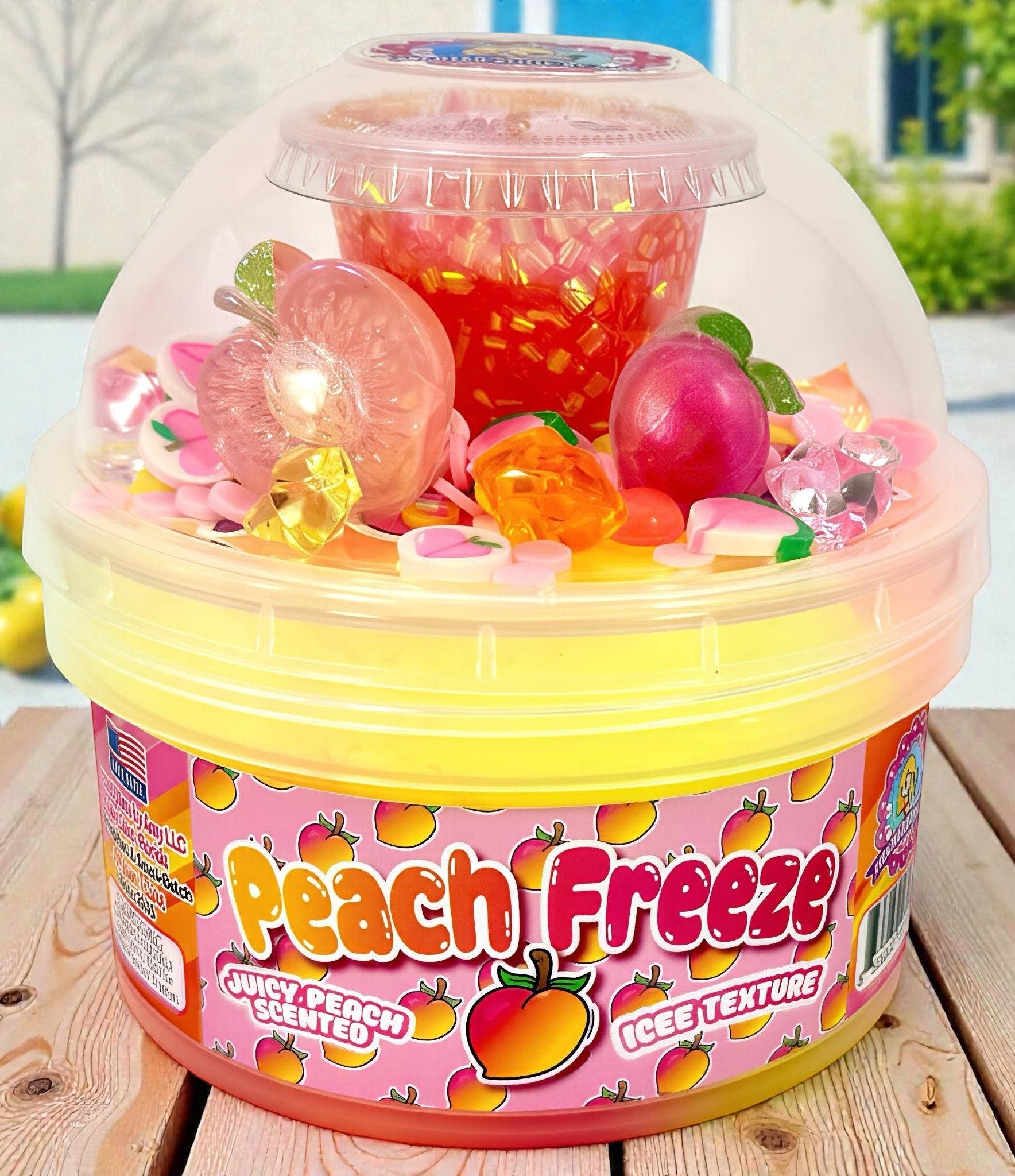 Doodlations Peach Freeze iced texture slime with peach charms, glitter, and candy add-ins in a yellow bucket.