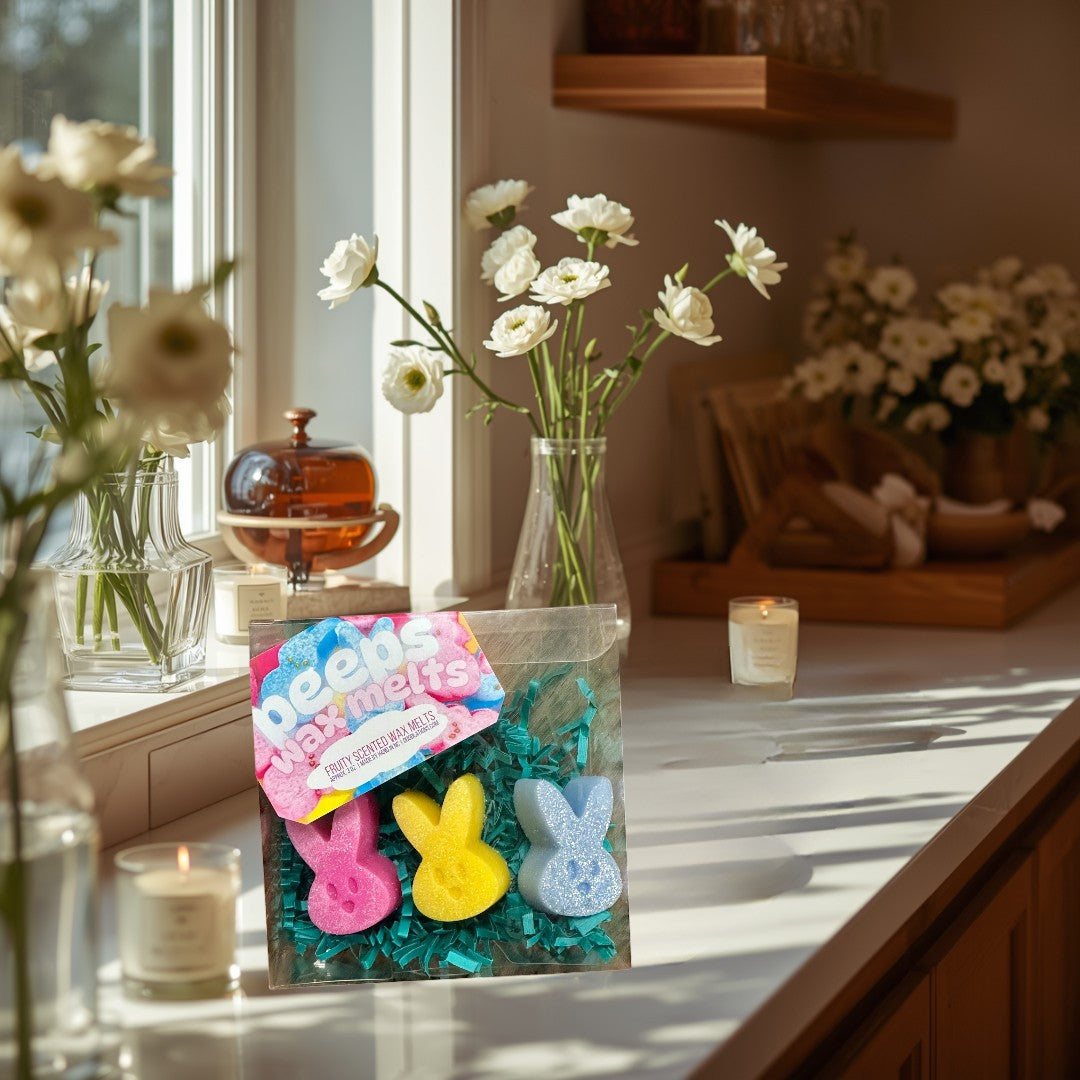 Doodlations Peeps wax melts in pink, yellow, and blue bunny shapes with glitter, nestled in green crinkle paper.