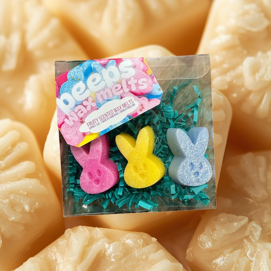 Doodlations Peeps wax melts in pink, yellow, and blue bunny shapes with glitter, nestled in green crinkle paper.