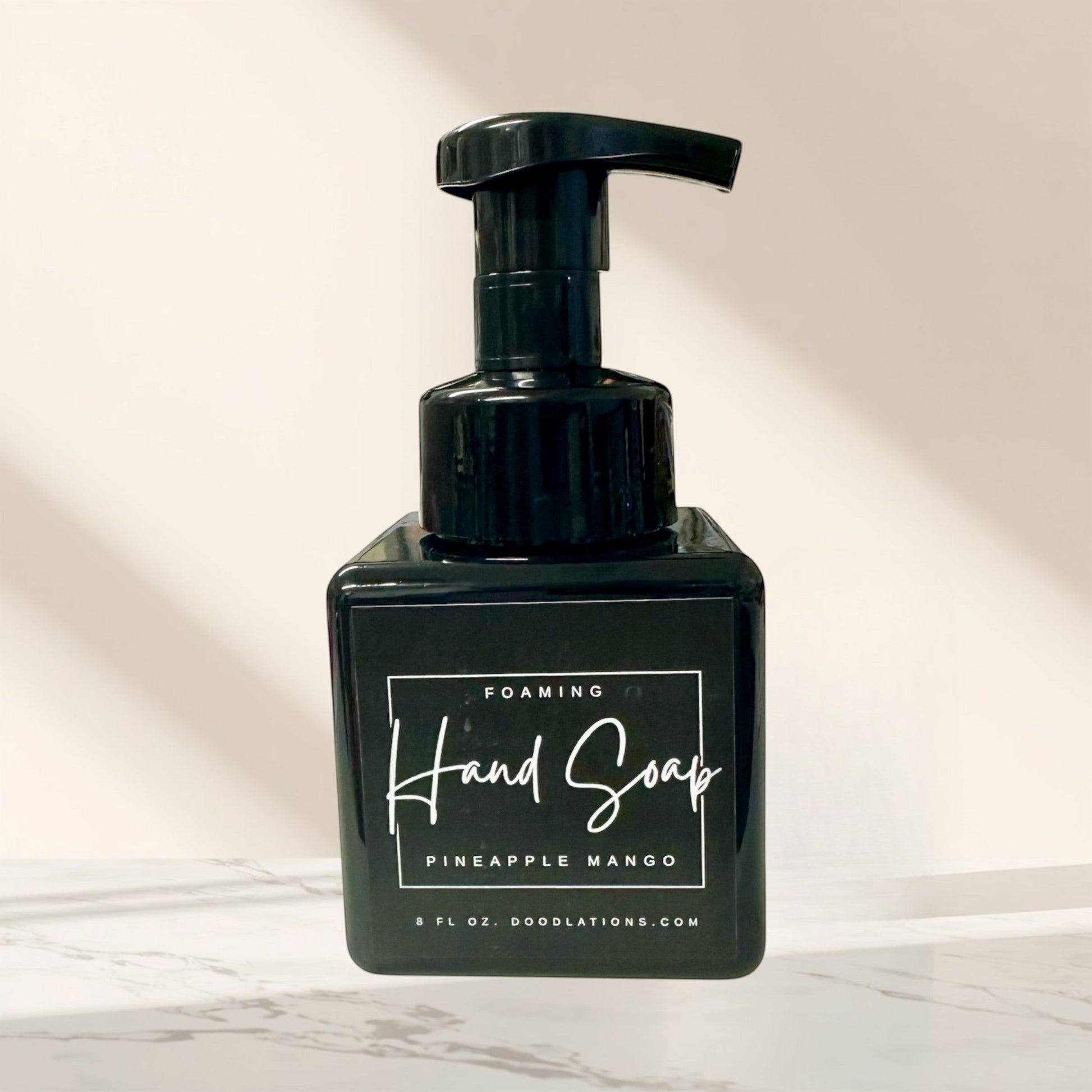 Doodlations Pineapple Mango foaming hand soap in a black square bottle with a black pump dispenser. Tropical scent.