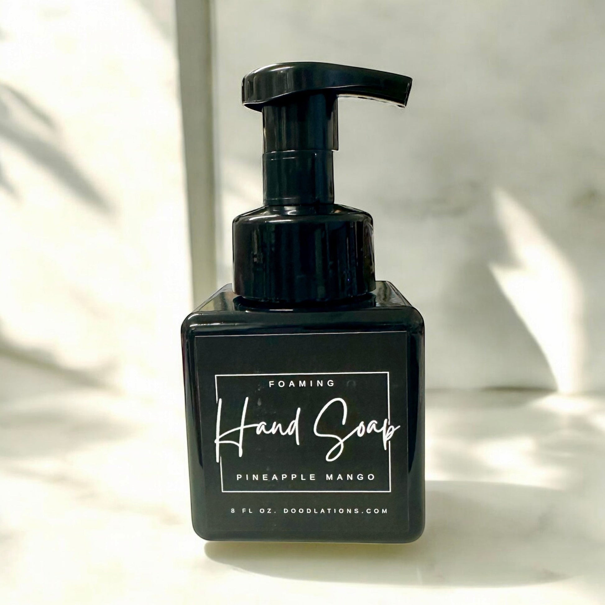 Doodlations Pineapple Mango foaming hand soap in a black square bottle with a black pump dispenser. Tropical scent.