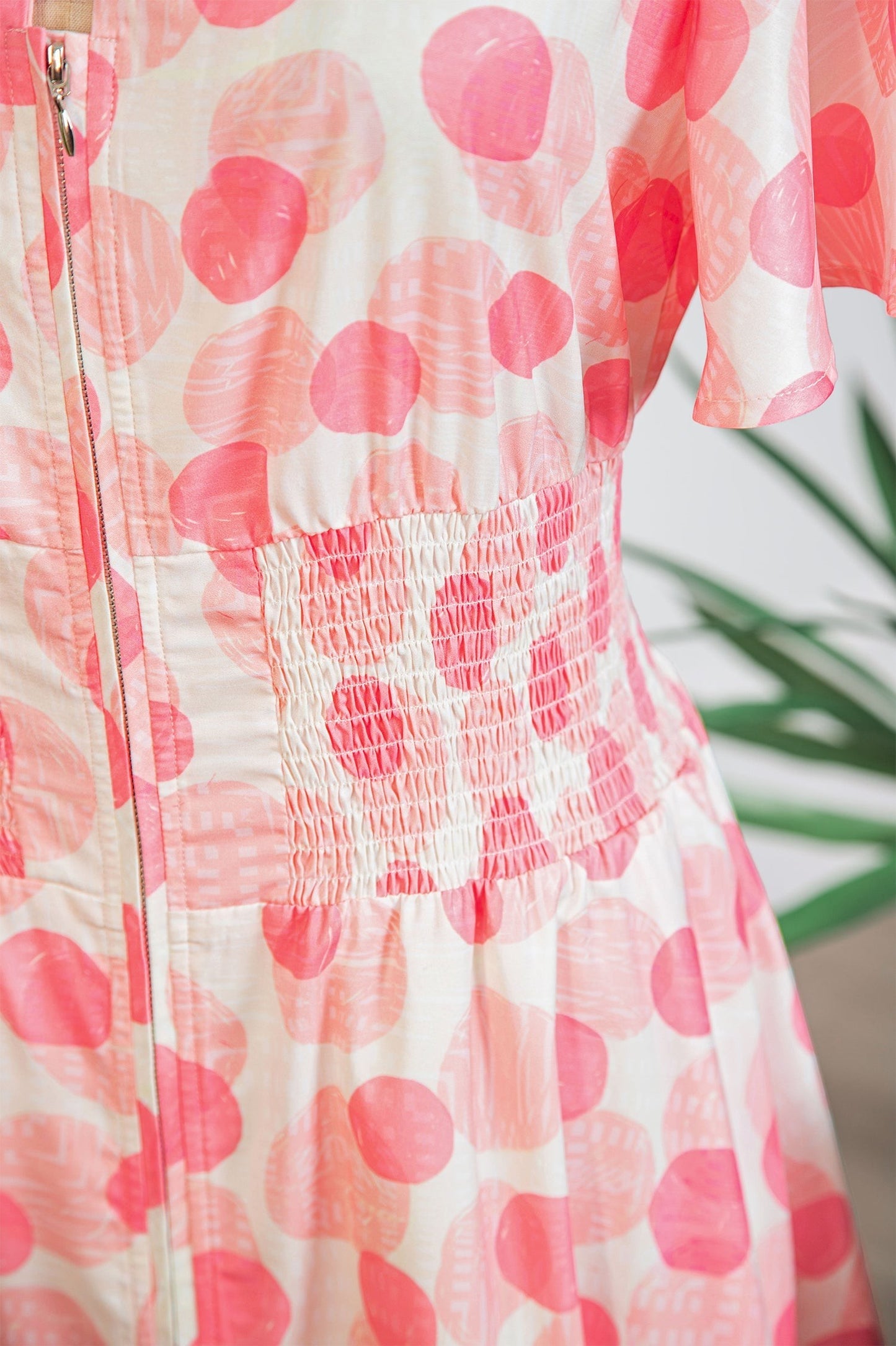 Doodlations Coffee Bar & Boutique white midi dress with pink polka dots, smocked waist, flutter sleeves, and zip front.