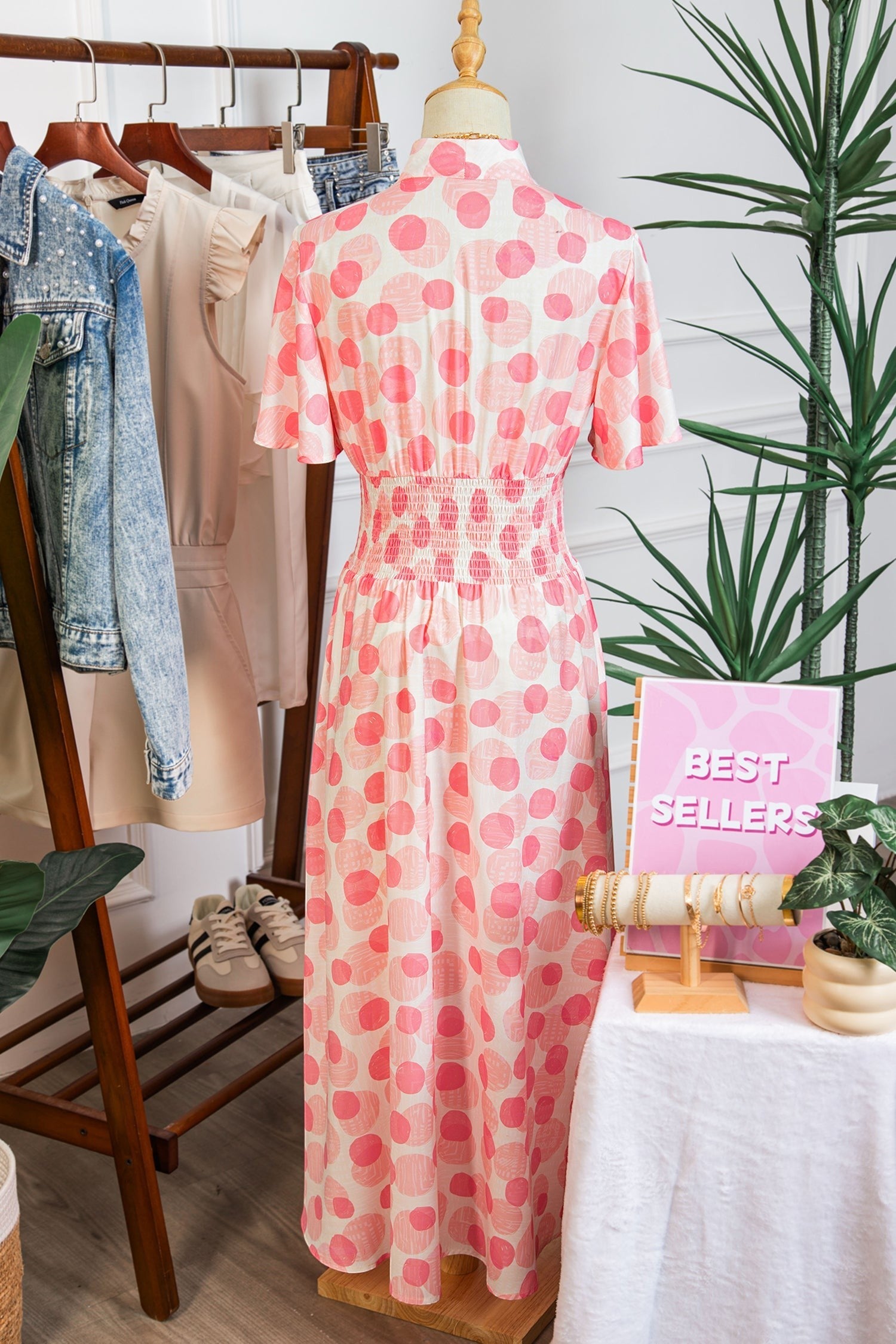 Doodlations Coffee Bar & Boutique pink and white polka dot midi dress with smocked waist and flutter sleeves.