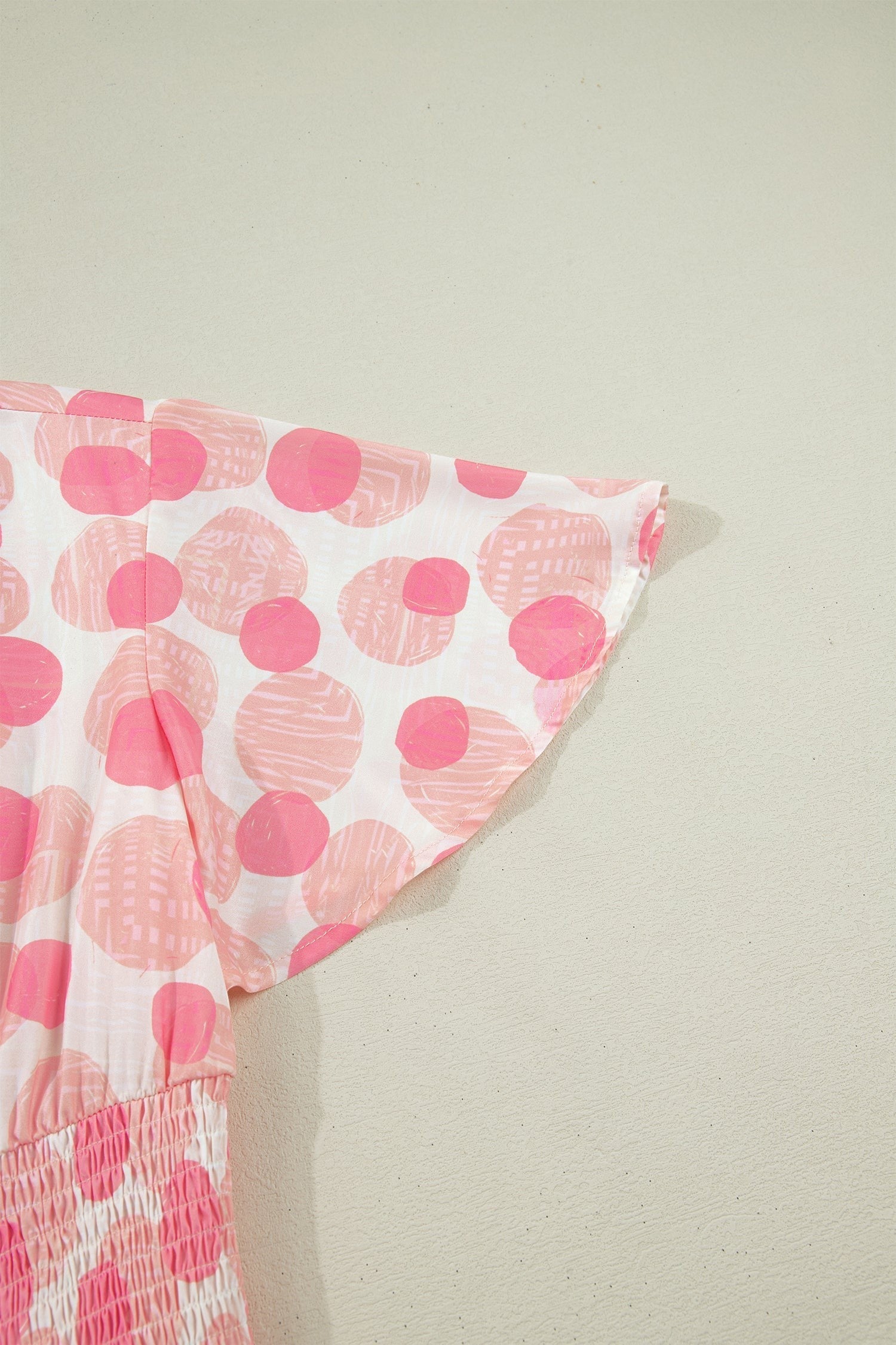 Doodlations Coffee Bar & Boutique pink and white polka dot midi dress with smocked waist and flutter sleeves.