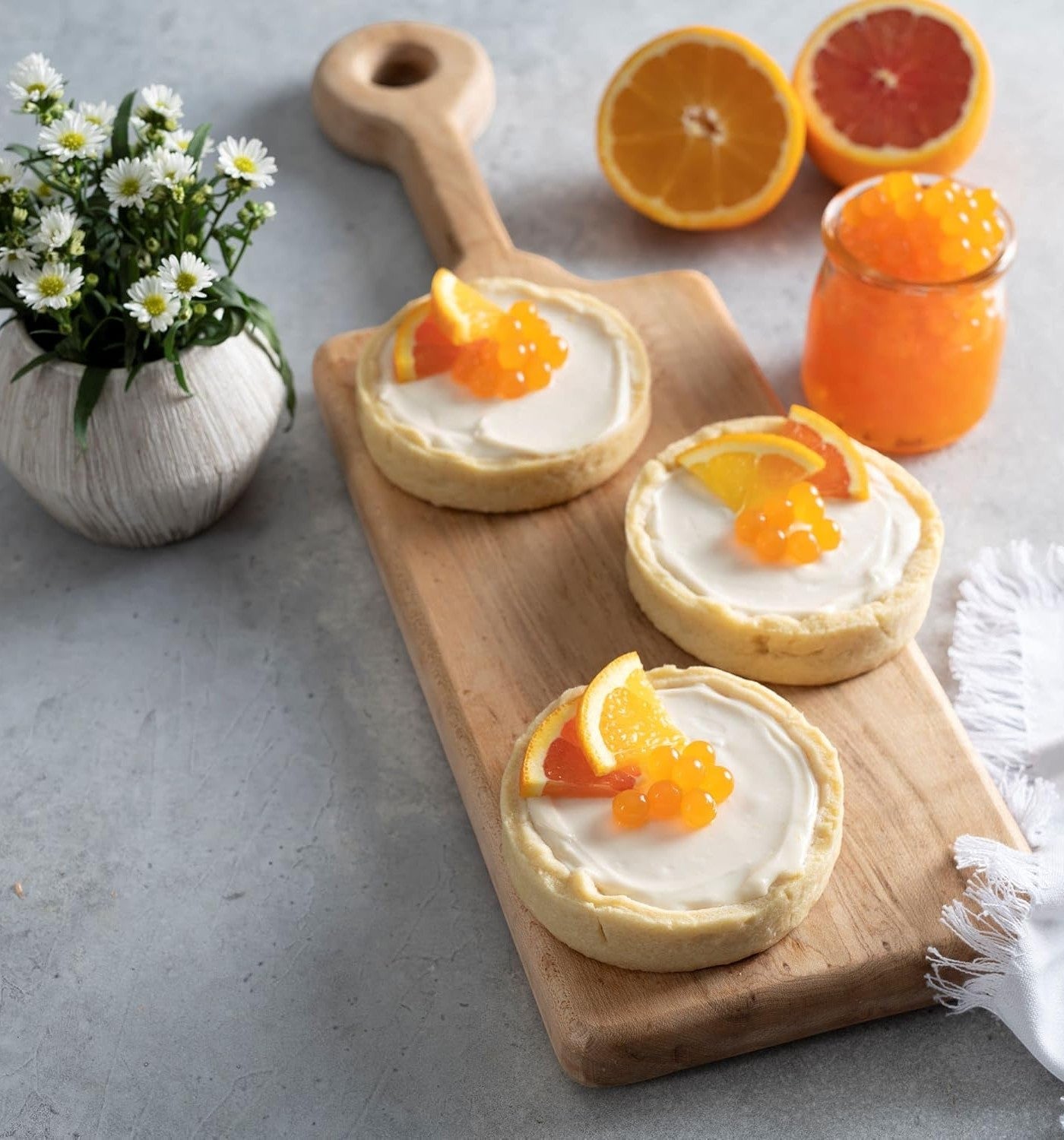 Doodlations Coffee Bar & Boutique Pomegranate Bursting Balls topping creamy tarts garnished with orange slices.