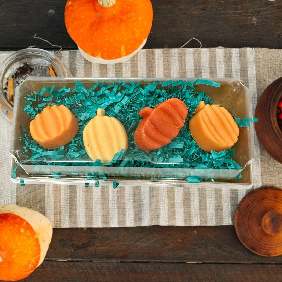 Doodlations Smashed Pumpkin wax melts in orange and yellow pumpkin shapes, nestled in teal crinkle paper.