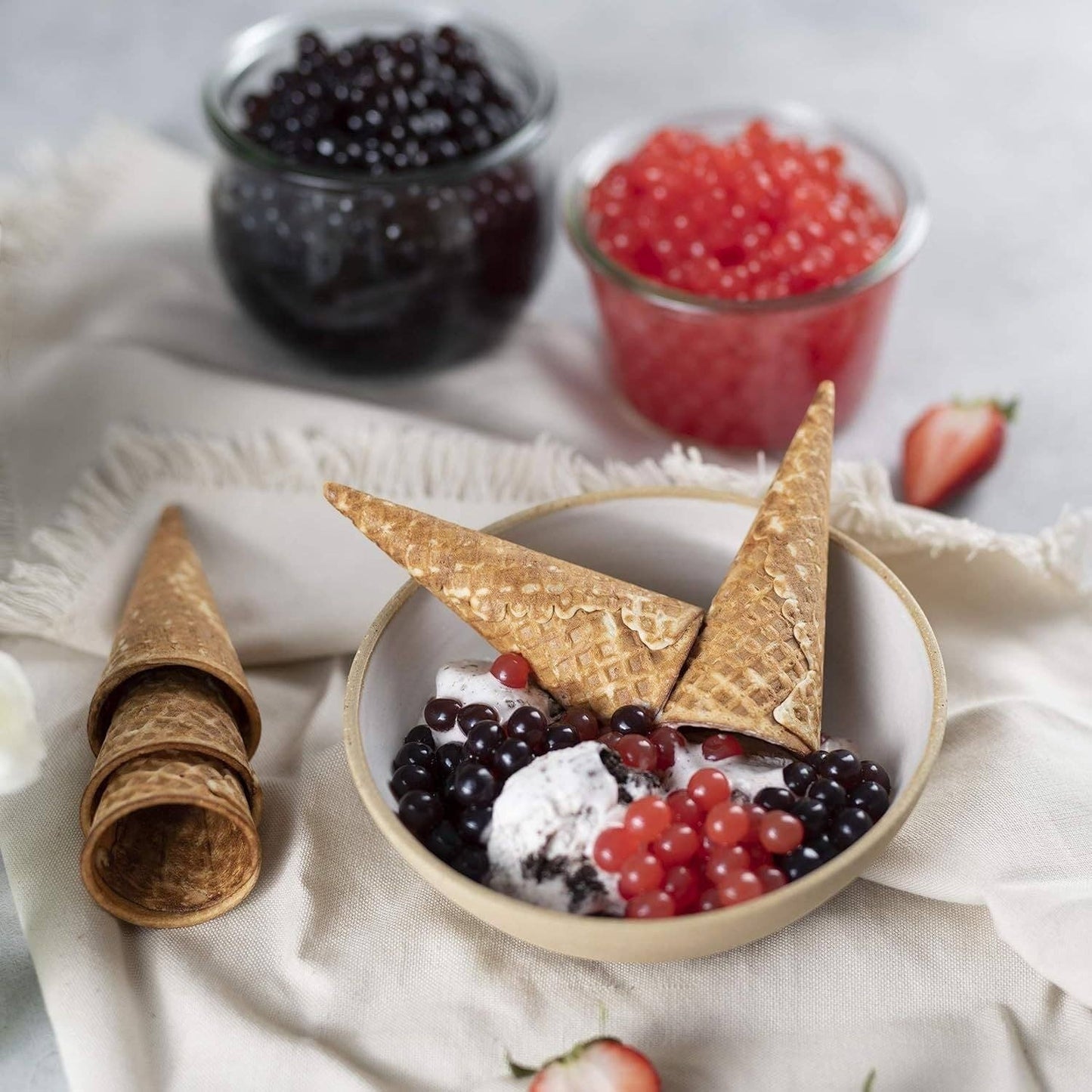 Doodlations Coffee Bar & Boutique strawberry bursting balls topping ice cream with waffle cones and black popping boba.