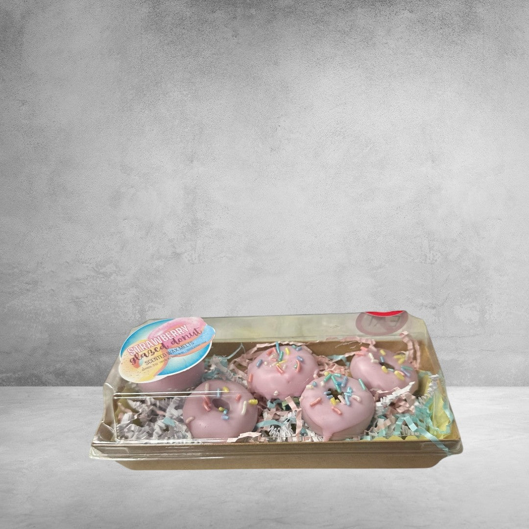 Doodlations Strawberry Glazed Donut wax melts shaped like donuts with pink frosting and sprinkles. Packaged in a clear box with colorful crinkle paper.