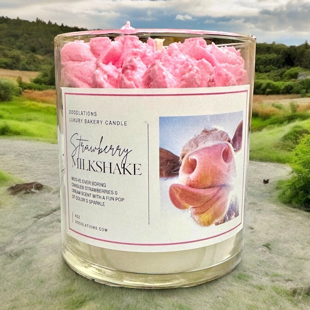Doodlations Strawberry Milkshake luxury candle with pink whipped topping and cow print label.