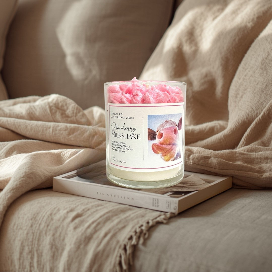 Doodlations Strawberry Milkshake luxury candle with pink whipped topping and cow print label.