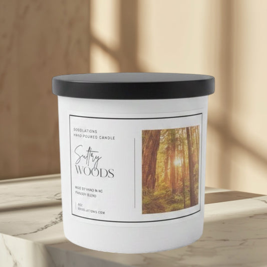 Doodlations Coffee Bar & Boutique Sultry Woods hand-poured candle with a forest scene label, featuring notes of mandarin, jasmine, amber, sandalwood, and musk.