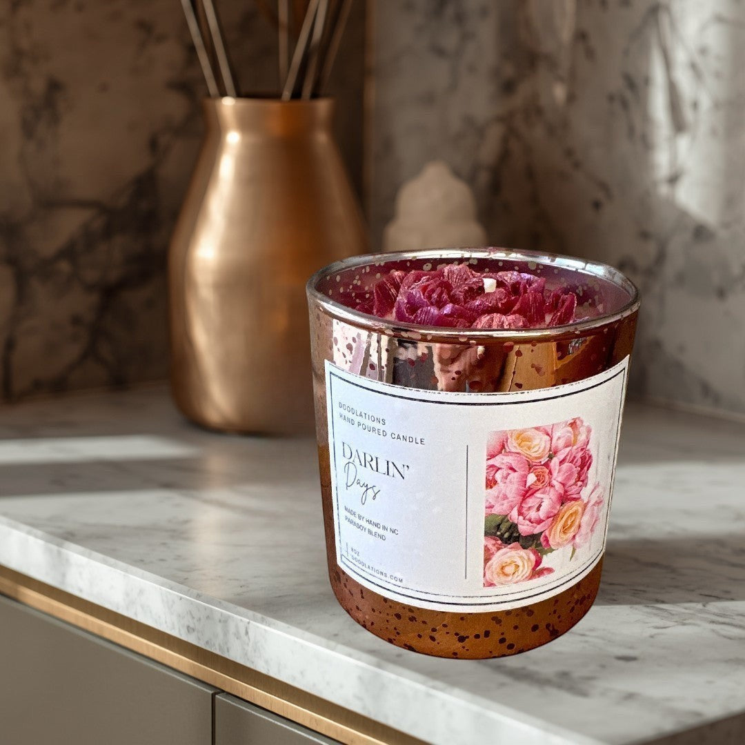 Doodlations Darlin' Days Floral hand-poured candle in a rose gold mercury glass jar with pink and cream rose decorations.