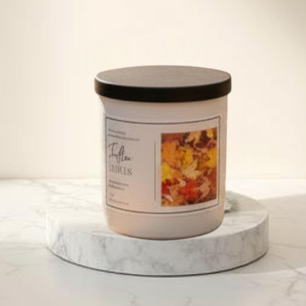 Fallen Leaves candle with wax leaf topping, next to a mug and grey blanket on a picnic table.