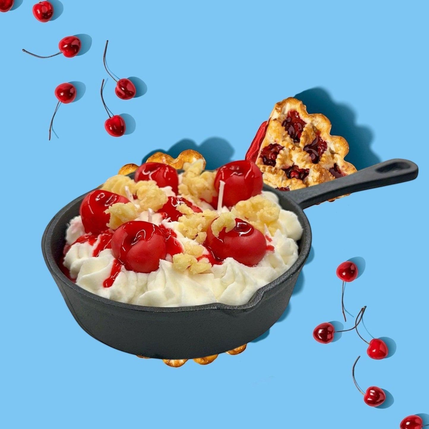 Cherry Yum Yum candle in a black iron skillet with white wax frosting, red wax cherries, and crumble topping.