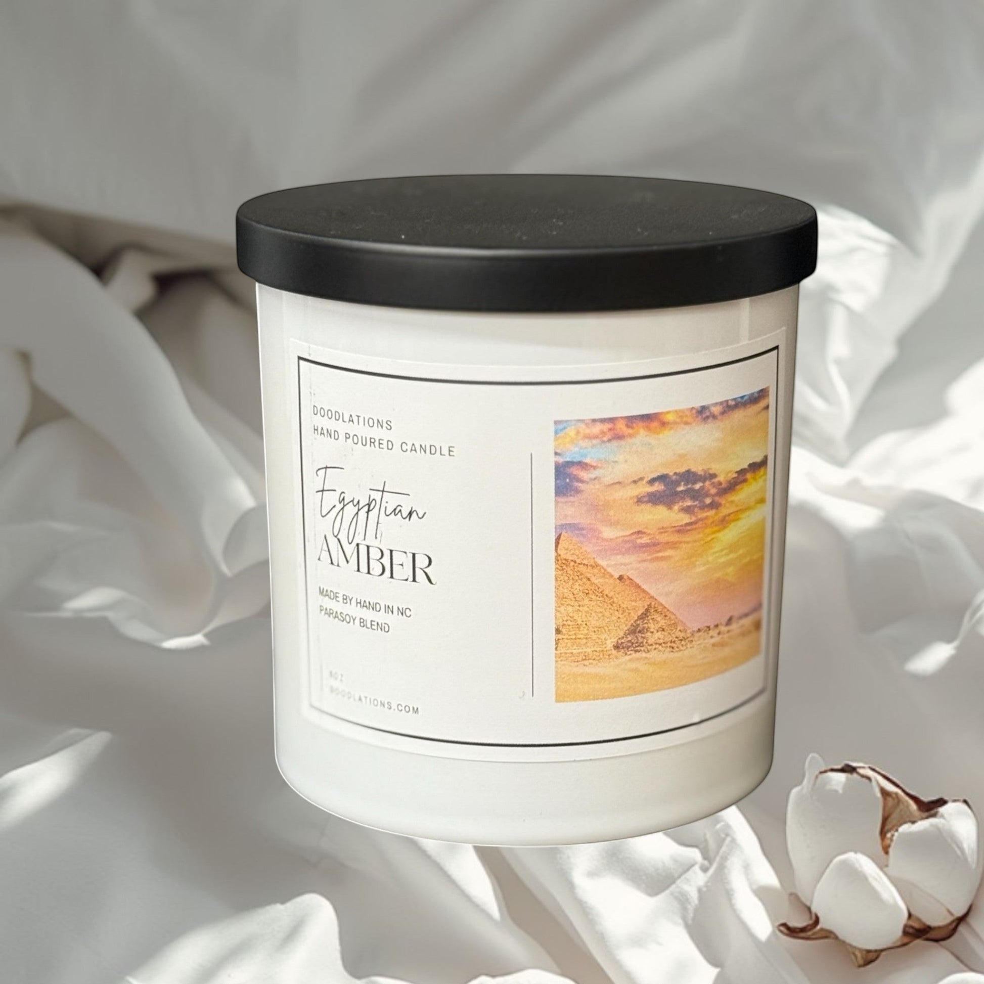 Egyptian Amber hand-poured soy blend candle in a white jar with a black lid.